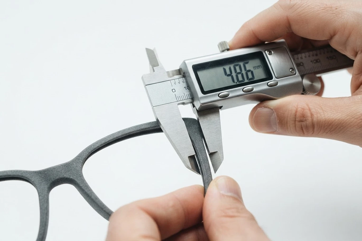 Close-up of designer hand measuring eyewear frame with digital caliper